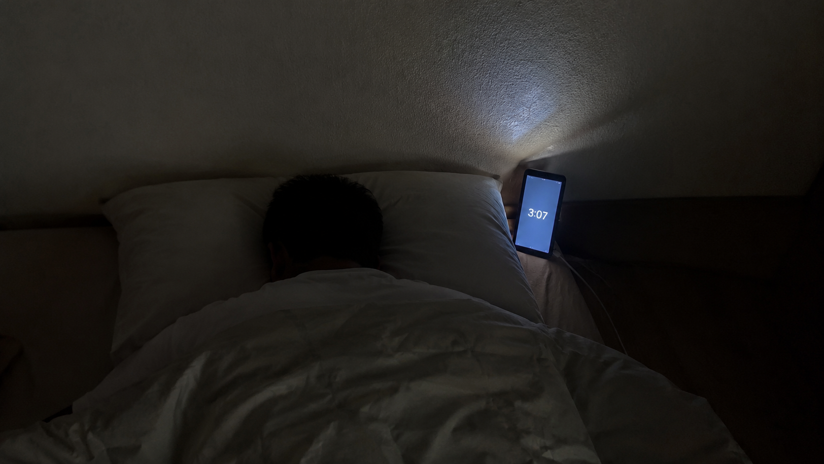 夜3時の暗い寝室、枕元のスマホ